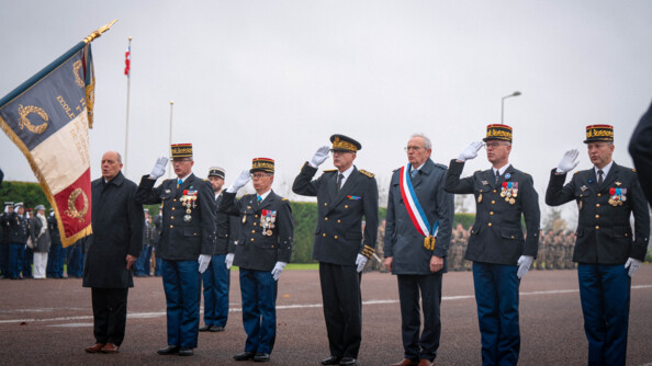 Six militaires se tiennent debout c&ocirc;te &agrave; c&ocirc;te, effectuant le salut, &agrave; l'occasion d'une c&eacute;r&eacute;monie militaire. Un &eacute;lu, portant l'&eacute;charpe tricolore en travers de la poitrine, se tient &agrave; leurs c&ocirc;tes