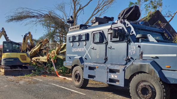 Un véhicule blindé de la gendarmerie, tracte des troncs d'arbres arrachés, sur une route, après le passage du cyclone Garance sur l'île de la Réunion.
