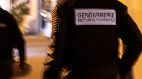 Un gendarme en noir de dos portant une chasuble "gendarmerie section de recherches"