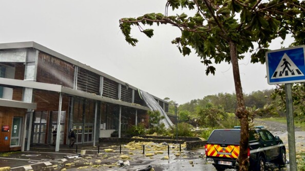 Un véhicule de la gendarmerie est stationné à proximité d'un gymnase, sur un route dévastée après le passage du cyclone Garance sur l'île de la Réunion.