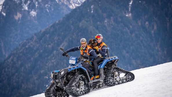 Deux gendarmes du PGHM avec le chien de l'équipe cyno sur une moto-neige dans la neige.