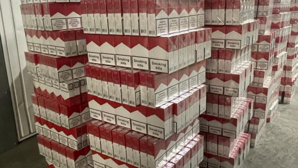 Plusieurs piles de cartouches de cigarettes dans un hangar.