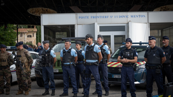 Huit gendarmes - sept hommes et une femme - se tiennent debout devant un v&eacute;hicule de la gendarmerie et un b&acirc;timent, sur la fa&ccedil;ade duquel est inscrit "Poste fronti&egrave;re Saint-ludovic Menton". A leurs c&ocirc;t&eacute;s se tiennent aussi quelques militaires de l'op&eacute;ration Sentinelle. L'un porte un fusil en travers, sur le devant du corps