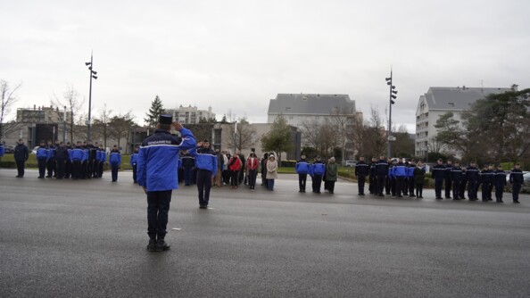 Des gendarmes et civils alignés en cérémonie devant une place