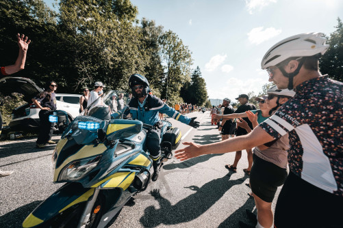 Un motocycliste de la gendarmerie sur la route tape dans les mains des spectateurs..