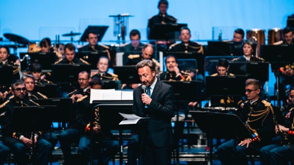 Stéphane Bern lit un docuemnt au micro devant l'orchestre de la Garde républicaine