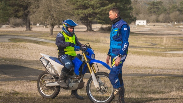 Une motarde de la gendarmerie face à son instructeur sur un terrain sauvage avec quelques arbres