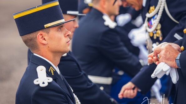 Portrait de profil d'un élève gendarme en tenue de cérémonie, les yeux levés vers son chef