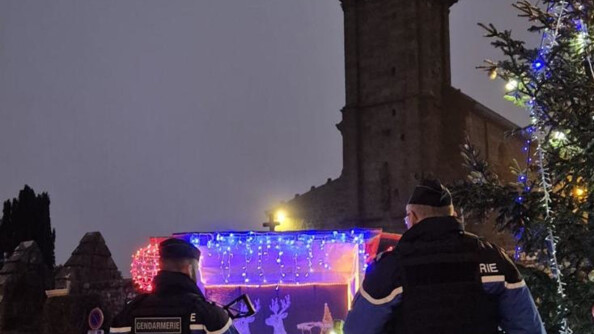 Deux gendarmes au pied d'une église devant des décorations de Noel