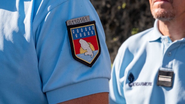 Deux gendarmes l'un derrière l'autre, avec l'insigne du Commandement de la gendarmerie de la Martinique sur le polo du premier.