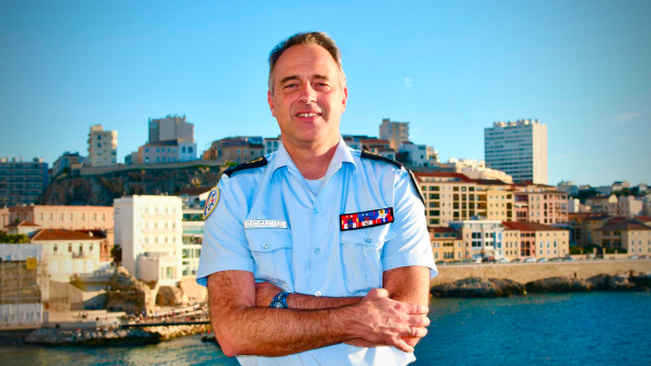 Un général de gendarmerie les bras croisé devant la mer et la côte marseillaise