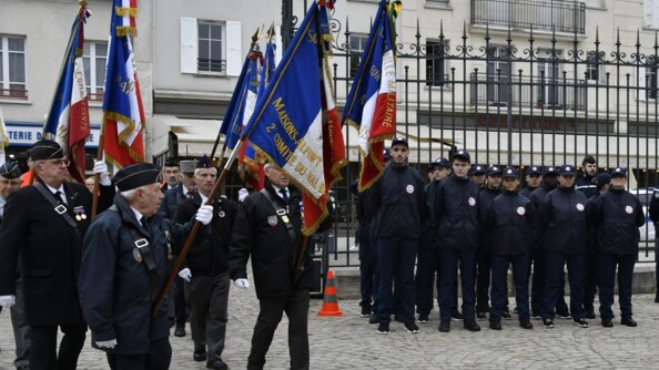 Des portes drapeaux et des jeunes du SNU devant une grille sur les pavés