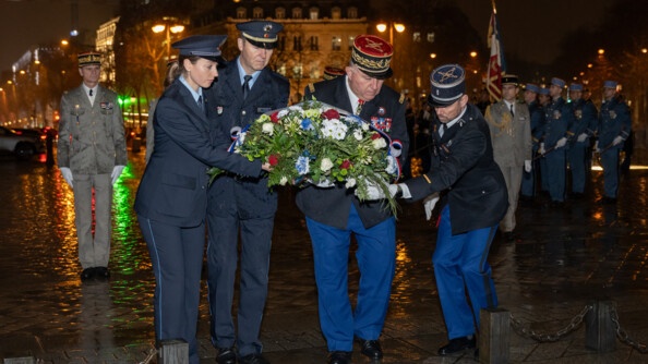 Deux policiers allemands et deux gendarmes fran&ccedil;ais dont un g&eacute;n&eacute;ral d&eacute;posent une gerbe sur les pav&eacute;s. A droite en arri&egrave;re-plan, des militaires. La nuit et la pluie sont sur la ville