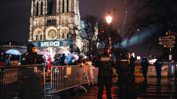 Photo de gendarmes mobile devant le parvis de Notre-Dame. Derrière sur la cathédrale, il est écrit "MERCI"