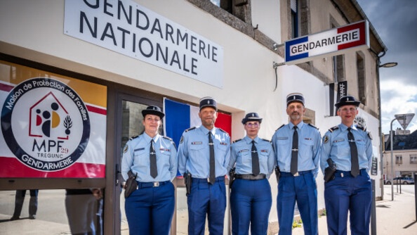 Cinq gendarmes debout les mains dans le dos devant la maison de protection des familles de Trégunc. Au dessu de l'entrée l'inscription "gendarmerie nationale" et sur la vitre le logo et la maison de protection des familles