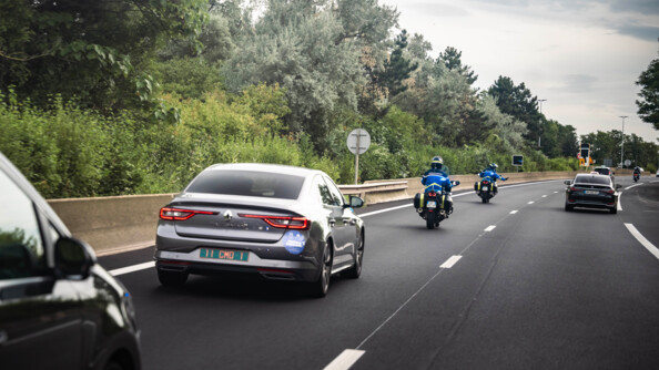 Motocyclistes escortant un convoi et faisant signe à un véhicule de s'écarter.