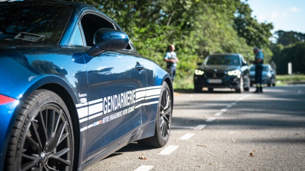 Au premier plan le véhicule rapide d'intervention (VRI), l'Alpine 110 de la gendarmerie. Au second plan les gendarmes contrôlent un véhicule.