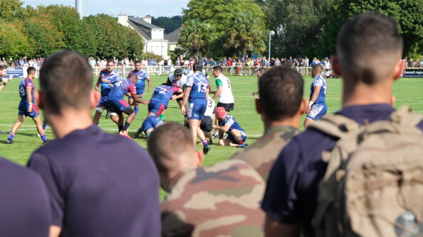 Match de rugby avec des militaires spectateurs au premier plan de dos