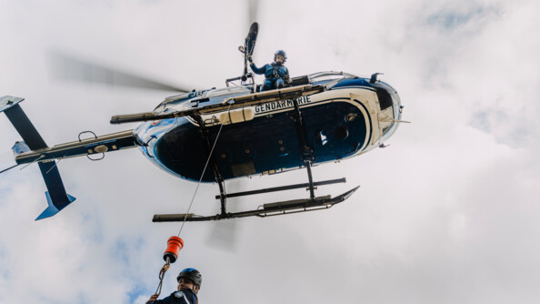 vue en contre plongée proche, d'un gendarme tenant un câble, en cours d'hélitreuillage, une gendarme étant hélitreuillée
