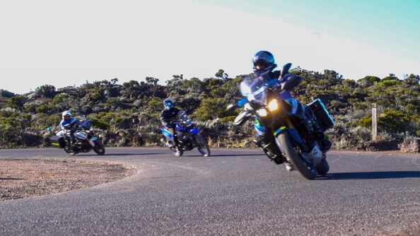 Sur la route, un motocycliste de la gendarmerie ouvre la voie. Derrière lui, un motard, civil le suit.