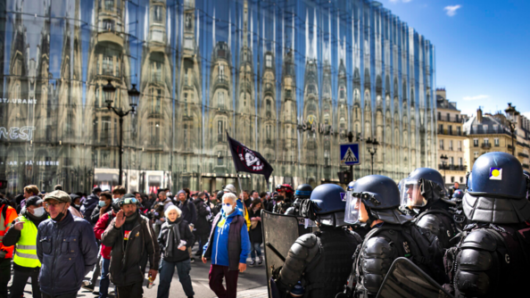 Des gendarmes mobiles sécurisent un cortège de manifestants dans une rue de Paris.