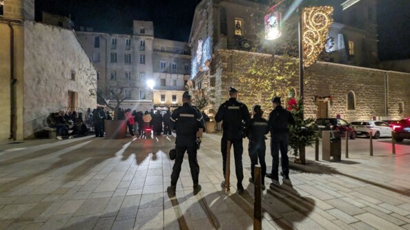 Quatre gendarmes de dos devant la foule dans une ville décorée pour Noël