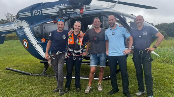 Quatre hommes civil dont Marc Lièvremont et un gendarme posent, tout sourires, devant un hélicoptère de la gendarmerie posé sur l'herbe