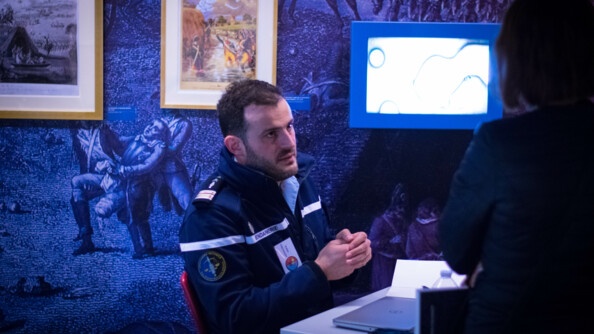 Le lieutenant-colonel Robin Fischhoff, lauréat du prix 2023 du roman de la gendarmerie nationale, assis à un bureau, échange avec des lecteurs, au salon littéraire de l'EOGN, le 1er avril.