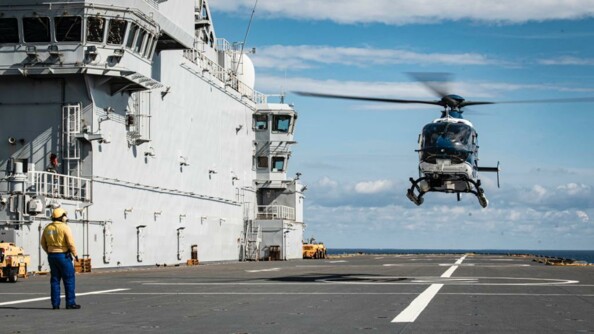 Un hélicoptère de la gendarmerie nationale en approche du pont du porte hélicoptères Mistral de la Marine nationale, d'où un signaleur le guide.