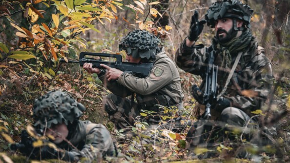 Trois cavaliers de la Garde agenouillés dans les bois. Celui de droite, Famas en bandoulière, pointe une direction face à lui de son bras droit ; son camarade, au centre de l'image, vise avec son arme vers la gauche de la photo. Le militaire au premier plan, à gauche, vise droit devant lui avec son Famas.