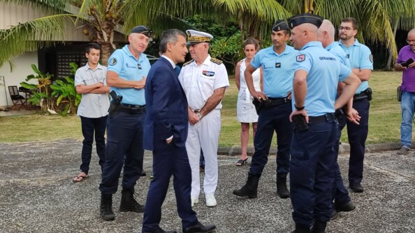 Le ministre discute avec des gendarmes aupremier plan, les familles se trouvent au second plan devant les habitations des militaires.