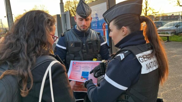 Deux gendarmes discutent avec une femme autour d'un flyer expliquant le harcèlement dans les transports