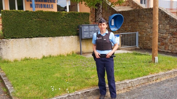 Portrait d'une sous-officier de gendarmerie en tenue de service courant devant sa brigade.