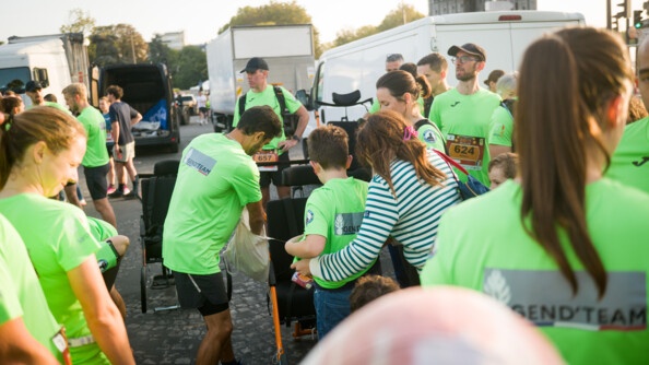 Les coureurs en t-shirt vert fluo installent un enfant dans une joëlette