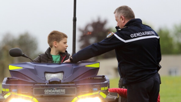Un enfant sur un quad gendarmerie, que tient un gendarme