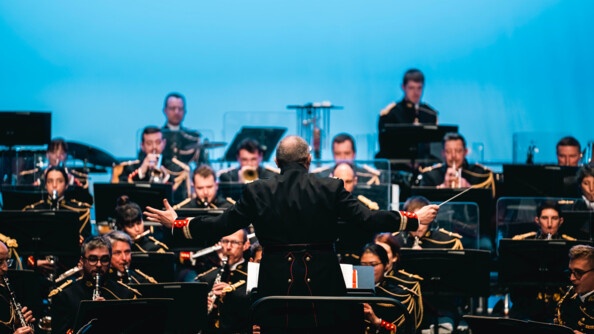 Le chef d'orchestre de la Garde, bras étendus, devant ses musiciens