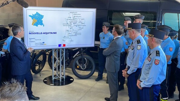 Présentation de la carte des nouvelles brigades de gendarmerie sur un écran, à Tonneins, dans le Lot-et-Garonne. A gauche de l'écran le ministre de l'Intérieur et des Outre-mer, Gérald Darmanin, et une gendarme derrière lui. A droite de l'écran, le président de la République Emmanuel Macron, le général d'armée Christian Rodriguez, directeur général de la gendarmerie nationale, le général de corps d'armée Samuel Dubuis, commandant de la Région de gendarmerie Nouvelle-Aquitaine, et plusieurs gendarmes.