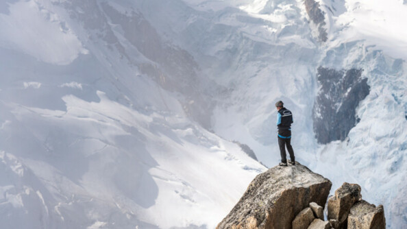 Un gendarme sur le haut d'un rocher devant la montagne.