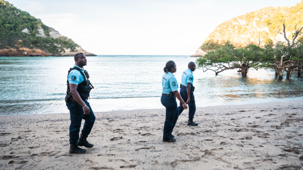 Trois réservistes de profil patrouillent le long de la plage.
