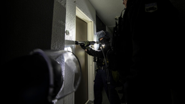 Un groupe de gendarme qui s'appr&ecirc;tent &agrave; inspecter une porte. L'un d'entre eux tiens une lampe de torche et essaie d'ouvrir la porte.