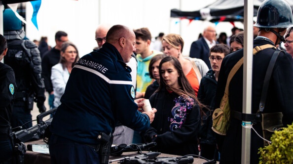 Un gendarme, de dos, présente des armes aux visiteurs des Journées portes ouvertes.