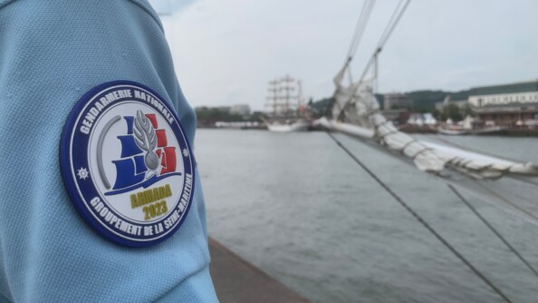 Photo de la rondache de l'Armada 2023. Au centre, des voiles au couleur du drapeau français avec la grenade de la gendarmerie. Ecrit en dessous en lettre d'or, Armada 2023.