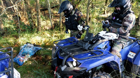 Deux gendarmes en treillis dont un sur un quad gendarmerie ramassent des déchets dans les bois