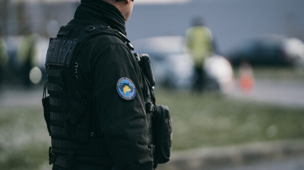 Vue de trois-quart dos d'un gendarme mobile de l'escadron Guépard de Satory. Un écusson "Alerte Guépart - GBGM" est apposé sur son bras droit