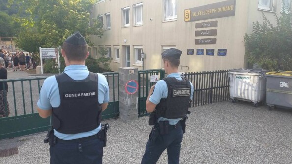 Deux gendarmes devant l'entrée d'un collège.