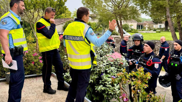 Deux gendarmes et un pompier revêtus d'une chasuble jaune fluo, en hauteur, s'adressent à des pompiers casqués
