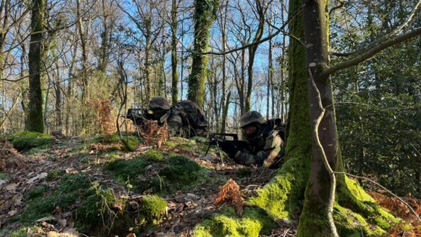 Deux gendarmes, en tenue de combat, dans la for&ecirc;t en entra&icirc;nement allong&eacute;s au sol tenant un FAMAS.