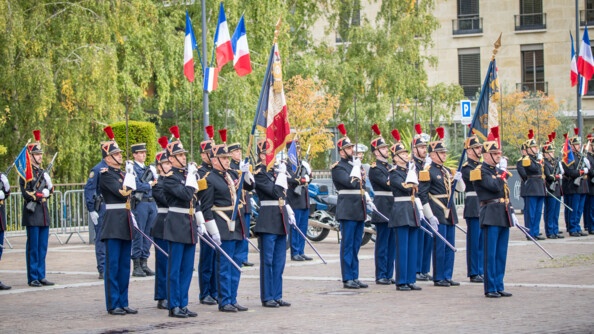 Des gadres de la garde républicaine debout sur un parvis. Certains portent des drapeaux