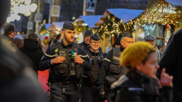 Deux gendarmes souriant au milieu de la foule d'un marché de Noël