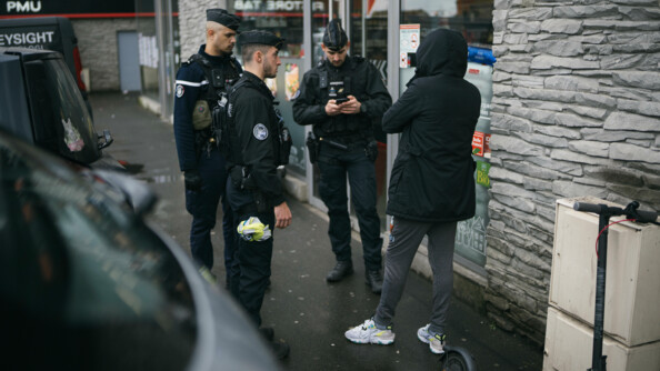 Trois gendarmes procèdent au contrôle d'un piéton au pied de bâtiments